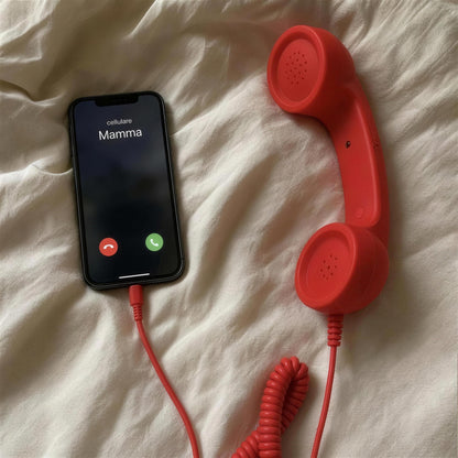 Cornetta telefono retrò rossa collegata allo smartphone sul letto